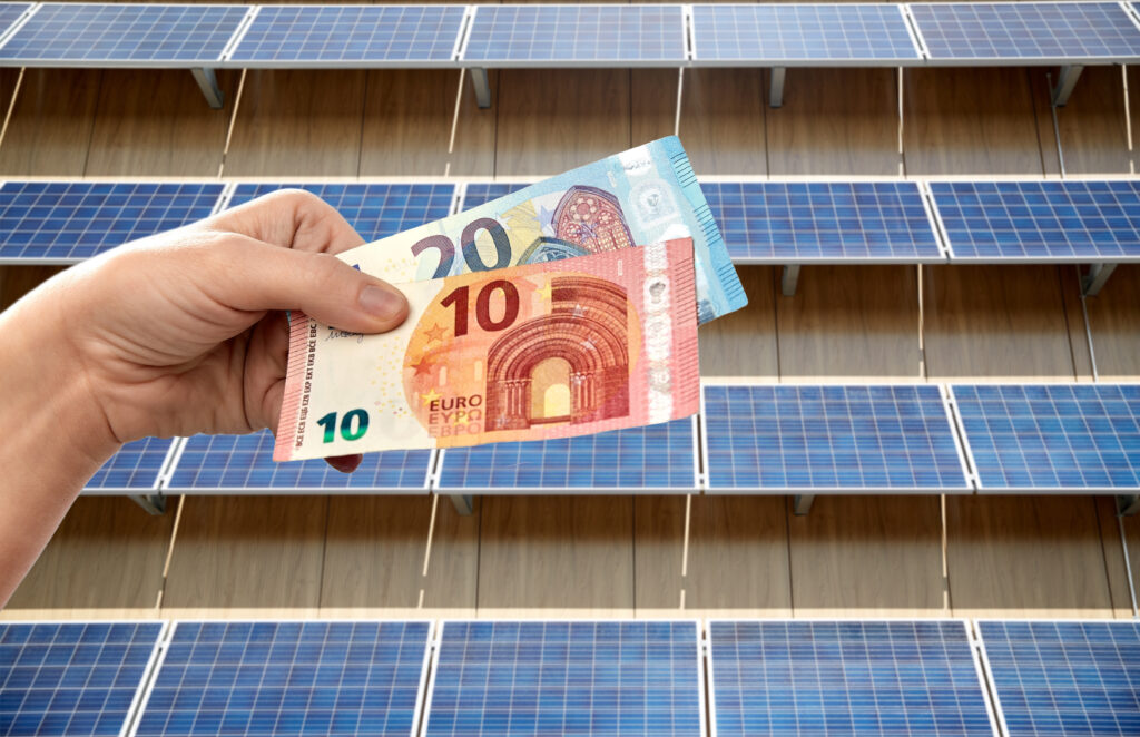 Hand met eurobiljetten voor zonnepanelen als symbool voor extra kosten voor zonnepaneeleigenaars in 2027.
